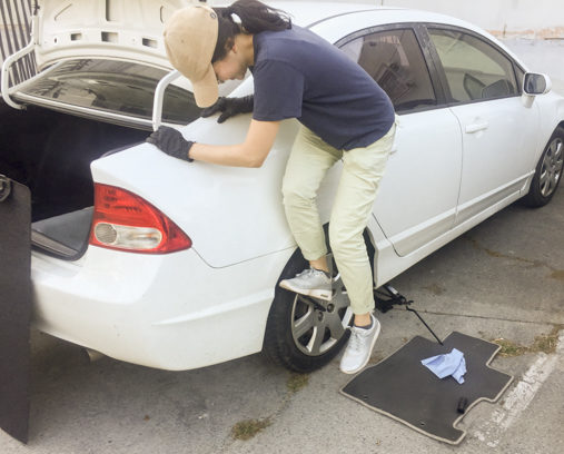 photo of someone standing on a lug nut wrench to remove lug nuts from a wheel